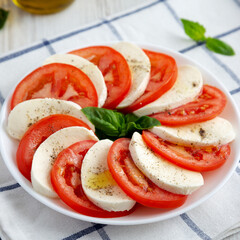 Homemade Caprese Salad with Mozzarella, Tomato and Basil on a white plate, low angle view.