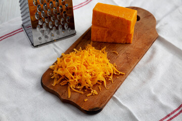Shredded Sharp Cheddar Cheese on a rustic wooden board, side view.