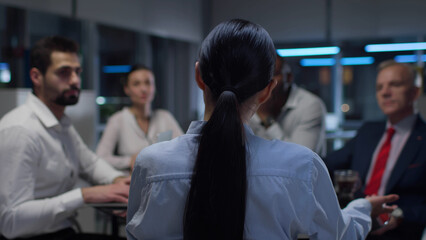 Back vuew of bsinesswoman leading corporate meeting with employees