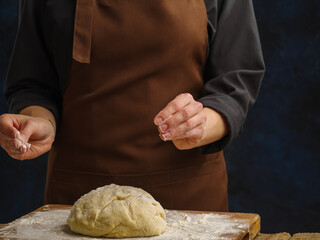 Dough prepared by the chef on a wooden cutting board. Dark background. Minimalism. cooking pasta, pizza. Close-up. Recipes, cooking. Restaurant, home cooking, hotel, pizzeria, bakery.