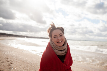Beatuful woman with over weight body walking in the beach, The plus size model wearing jeans, the warm knitted blanket and sweater. the wind in the bich have fun with hairs