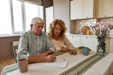 Woman looking at husband writing letter on paper