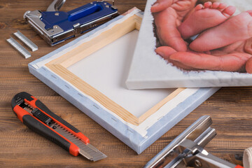 The business of printing photos on canvas, a finished painting and a tool for stretching the canvas on a stretcher