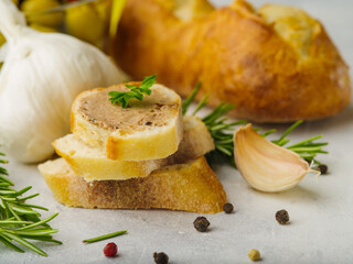 Appetizing pieces of foie gras, bread, sprigs of rosemary and grains of pepper on a white background. Festive dish, restaurant, hotel, cafe, advertising, banner.