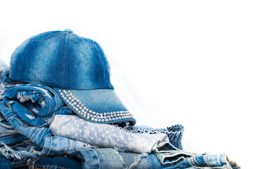 A stack of jeans and a cap neatly folded on a white background. Denim closeup of various designs....