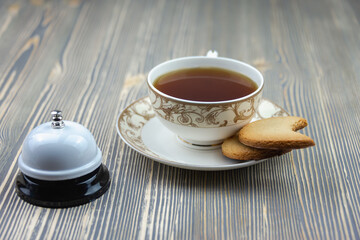 Tea in a cup and biscuits, staff call bell. Concept: good morning, tea time, breakfast.