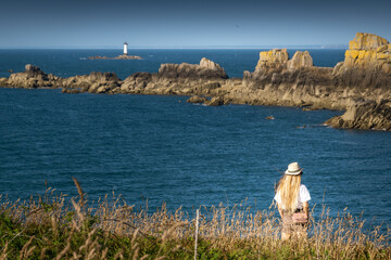 Rear view of woman in hat overlooking sea and cliff