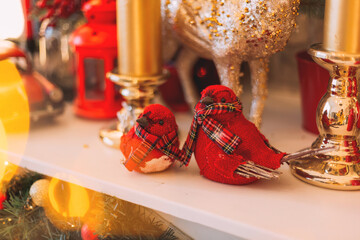 christmas decorations in a bright interior. red fabric birds bullfinches on the fireplace