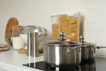 Pot and saucepan on electric stove in kitchen. Cooking utensils