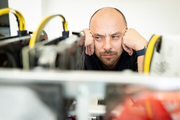 Young programmer adjusting cryptocurrency mining rig to optimal operational settings. High quality...