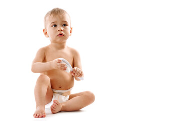 Little boy in diaper sitting and playing with brush.