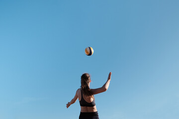 Fototapeta na wymiar Athlete jumps and kicks a volleyball. Summer sport Beach volleyball.