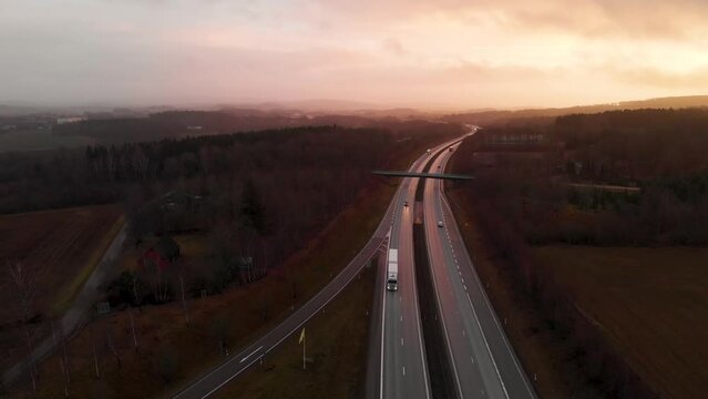 Aerial drone footage of European route E6 North of Halmstad, Sweden thoroughfare highway system with cars driving during sunrise sunset with golden hour late evening and morning left to right abstract