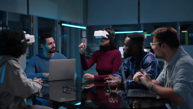 Young diverse start-up team discuss business strategy wearing vr headset late in office
