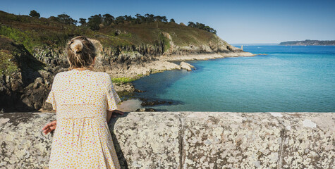 Woman leaning on embankment overlooking sea