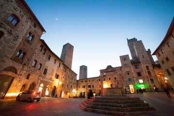 Italia, Toscana, Siena, il paese di San Gimignano con luci della sera. Piazza della Cisterna.