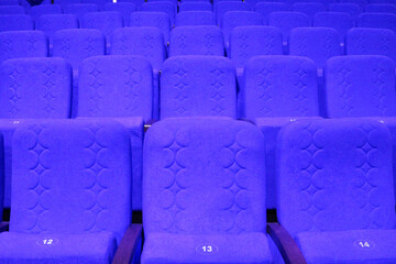 Fototapeta premium blue armchairs. Empty concert hall, theater chairs background ... color photo, empty cinema or concert hall. The red chairs in the cinema hall are illuminated by a light beam. Selective focus.