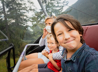 Boy taking selife with mother and brother while traveling on cable car