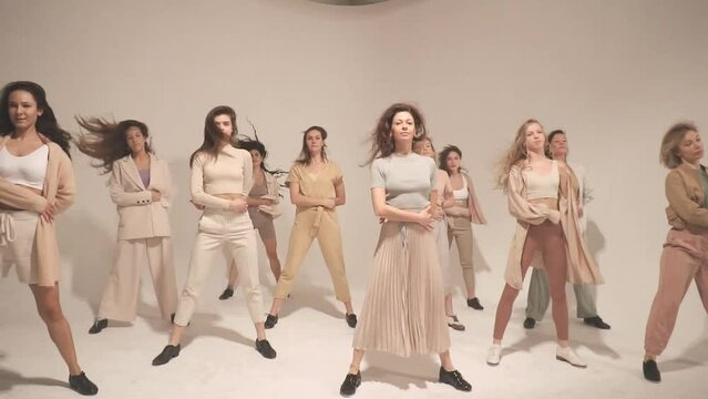 Group of  happy women dancing in white studio. Slow motion, natural, beige and pastel concept..