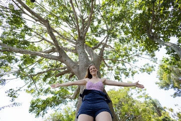 Young woman at a park on a beautiful sunny day with mobile phone.