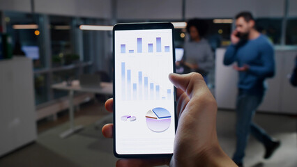Pov shot of business person analyze charts on smartphone in office