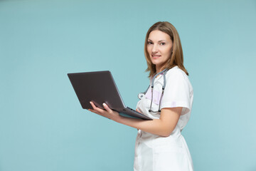 Beautiful female doctor with a stethoscope and a laptop, on a blue background. Online consultation. Copy paste. healthcare concept.