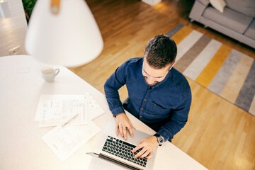 Top view of a handsome businessman working from home on his laptop.