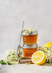 Delicious elderflower jelly in glass jars and fresh lemon with elder flowers. Homemade healthy food concept. 
Selective focus. Copy space.