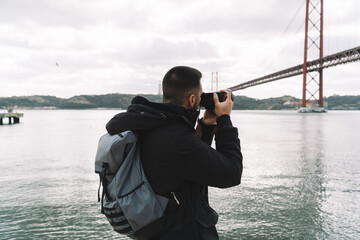 Obraz premium Photographer taking pictures of the bridge 25 April in Lisbon, Portugal
