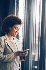 Casual beautiful black businesswoman using phone in her office