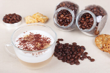 Breakfast with cappuccino, cookies, crackers and coffee beans on table.