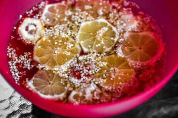 Fermentation and preparation of elderberry beverage, flower and lemon in bowl.