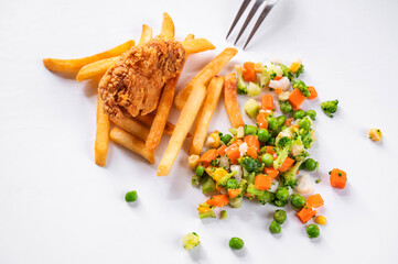 One piece of fried chicken meat in cornflake, french fries and vegetable on white.