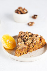 Homemade pie with tangerines and nuts in a plate on a light table. Healthy food, sugar, gluten and lactose free, vegan.
