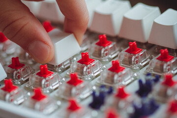 fingers placing a keycap on a white mechanical keyboard