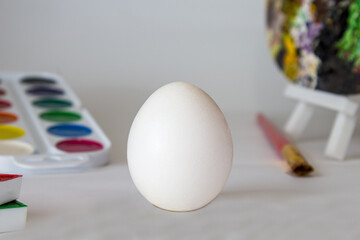 White Easter egg on a watercolor background. Simple holiday composition. Symbolism of the Easter egg festival concept. Art work, handmade, creativity with children for decoration for Easter