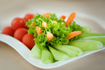 Peeled vegetables are on a plate. Tomatoes, cucumbers, carrots and lettuce. Children's menu.