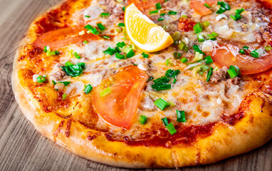 pizza with tuna fish and lemon on wooden background