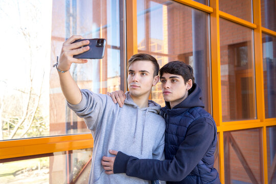 two gay college friends taking a picture with a cell phone
