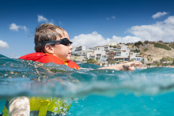 Boy wearing goggles with life jacket having fun in sea