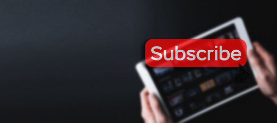 Subscribe banner. Online video subscription red button. Internet service on laptop digital tablet blured technology background. Social media concept. Streaming video.