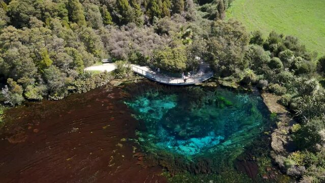 Tourists on viewing platform at Te Waikoropupu Springs. Beautiful cold water deep colorful spring in New Zealand - aerial drone