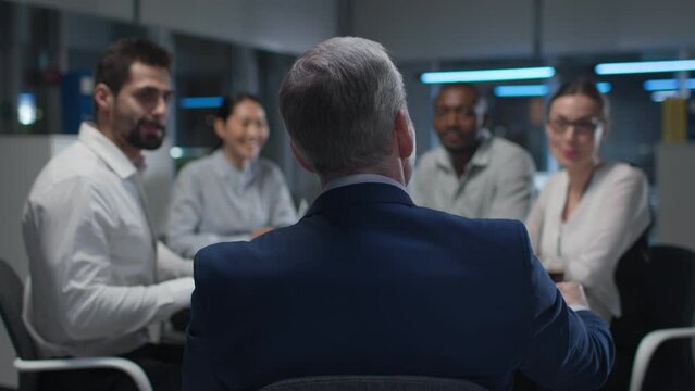 Back view of entrepreneur having meeting with business partners late in office