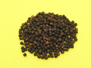 Black peppercorn on yellow background 