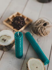 Multicolored beeswax candles with honeycomb texture on a wooden floor. Tree cuts and other accessories.