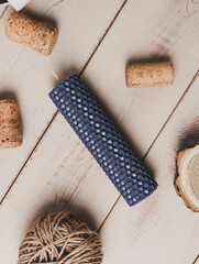 Multicolored beeswax candles with honeycomb texture on a wooden floor. Tree cuts and other accessories.