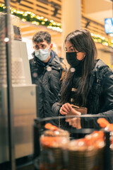 Young couple in face mask paying at the supermarket.