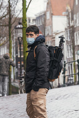 Boy wearing a mask and carrying a backpack on the canals of Amsterdam.