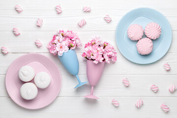 Two wineglass with spring flowers as a drink. Dessert in the morning for breakfast, top view. Cherry blossom on a white wooden table. Flat lay design. Pastel color card. Food background. Floral decor.