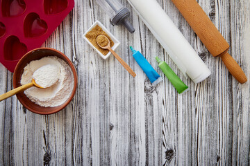Preparing for baking: heart-shaped silicone mold, rolling pin, confectionery syringe, glaze, flour, sugar. Copy space.